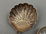 two silver spoons sitting next to each other on a table