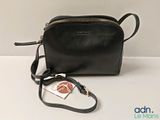 the small black purse is sitting on the table with a tag