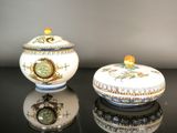 two small bowls sitting on a table with a clock in the background