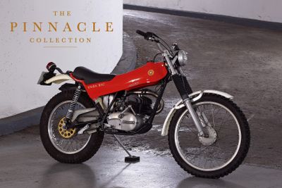 a red motorcycle parked in front of a white wall