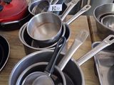 several pots and pans are lined up on a wooden table
