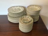 many plates stacked on a table with a wall in the background