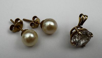 a pair of pearl and diamond earrings on a white surface