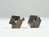 two pieces of silver metal are sitting on a white surface
