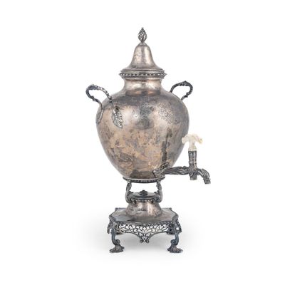 une théière en argent posée sur un socle, avec une bougie dessus