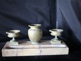 trois vases posés sur un socle en marbre, sur fond noir