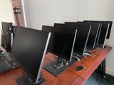 several computer monitors are lined up on a desk in front of a laptop