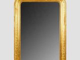 un miroir à cadre doré posé sur un mur blanc