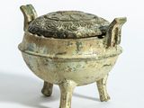 un petit pot en bronze muni d'un couvercle et posé sur un socle