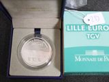 une pièce d'argent dans une boîte bleue sur laquelle est accrochée une étiquette