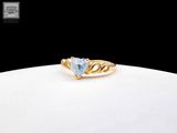 a close up of a gold ring with a heart shaped blue topaz stone
