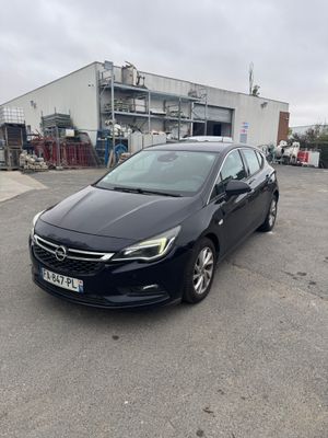 une Opel noire garée sur un parking à côté d'un immeuble