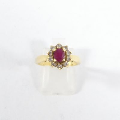 une bague en or jaune sertie d'un rubis entouré de diamants