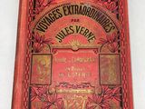 un vieux livre rouge orné de lettres dorées, posé sur une surface blanche