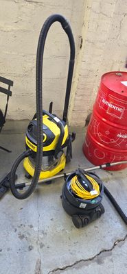yellow and black vacuum cleaner sitting on the ground next to a red barrel