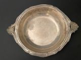 an antique silver plate on a black table with a black background