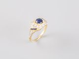 gros plan d'une bague en or avec un saphir et des diamants