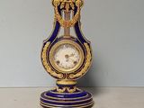 a blue and gold clock on a stand with a key