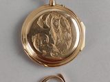a gold pocket watch and a ring on a table