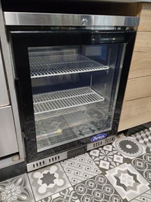 un réfrigérateur à porte vitrée dans une cuisine au sol carrelé