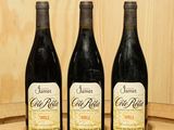 trois bouteilles de vin posées sur un tonneau