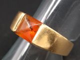 an image of a gold ring with an orange stone in it
