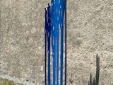 a blue sculpture on the ground next to a cement wall