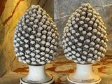 two white vases that have pine cones on them