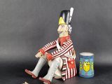 a figurine of a man sitting on a chair next to a can of beer