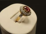 a gold ring with a red stone and diamonds on it