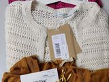 three sweaters and a purse are on a table with a price tag