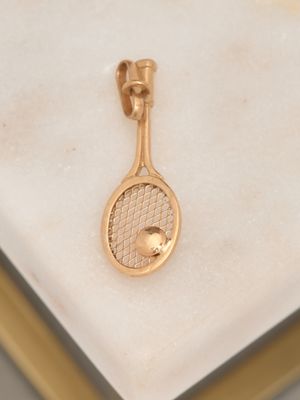 a gold tennis racket and ball on a marble surface