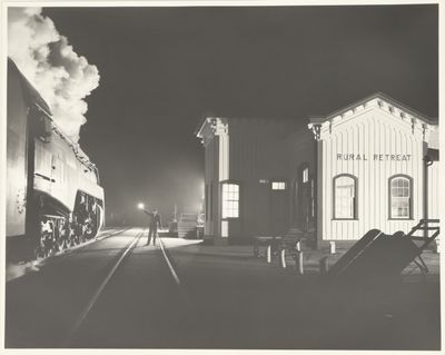 photographie en noir et blanc d'un train entrant en gare de nuit