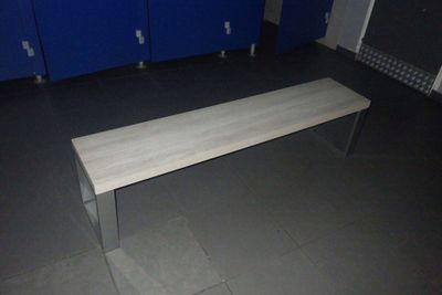 un banc au milieu d'une pièce, avec des casiers bleus en arrière-plan