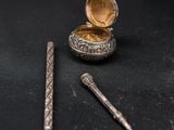 a small silver box with a pen next to it on a black surface