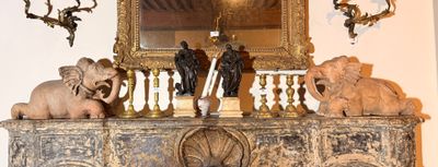 une cheminée sur laquelle sont posés des bougies, des statues et un miroir