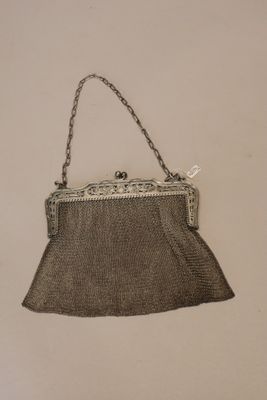 un vieux sac à main accroché au mur par une chaîne