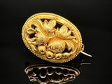 une image représentant une broche en or ornée de fleurs sur un fond noir