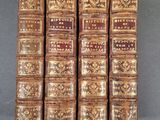 six vieux livres alignés en rangées sur une surface grise