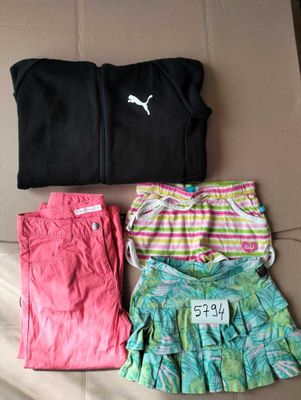 three pairs of shorts and a t - shirt laying on a bed
