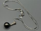 un gros plan d'un collier composé d'une perle noire montée sur une chaîne en argent