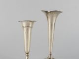 une paire de vases en argent posés sur une surface blanche
