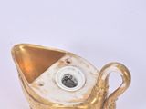 a small gold boat shaped object on a white surface