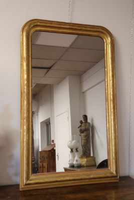 a gold framed mirror sitting on a table next to a vase