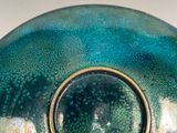 a green vase with a tag on it sitting on a table