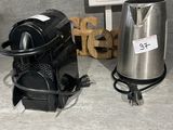 a silver coffee maker and a black coffee pot on the floor