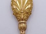 a gold spoon with a handle on a white surface