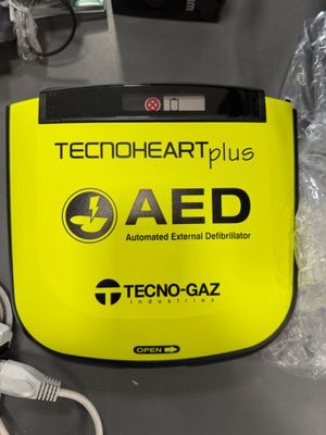 une boîte jaune de type AED surmontée d'un chargeur