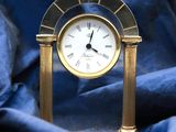 a small gold clock sitting on a blue cloth