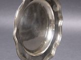 a silver plate on a metal stand on a gray surface